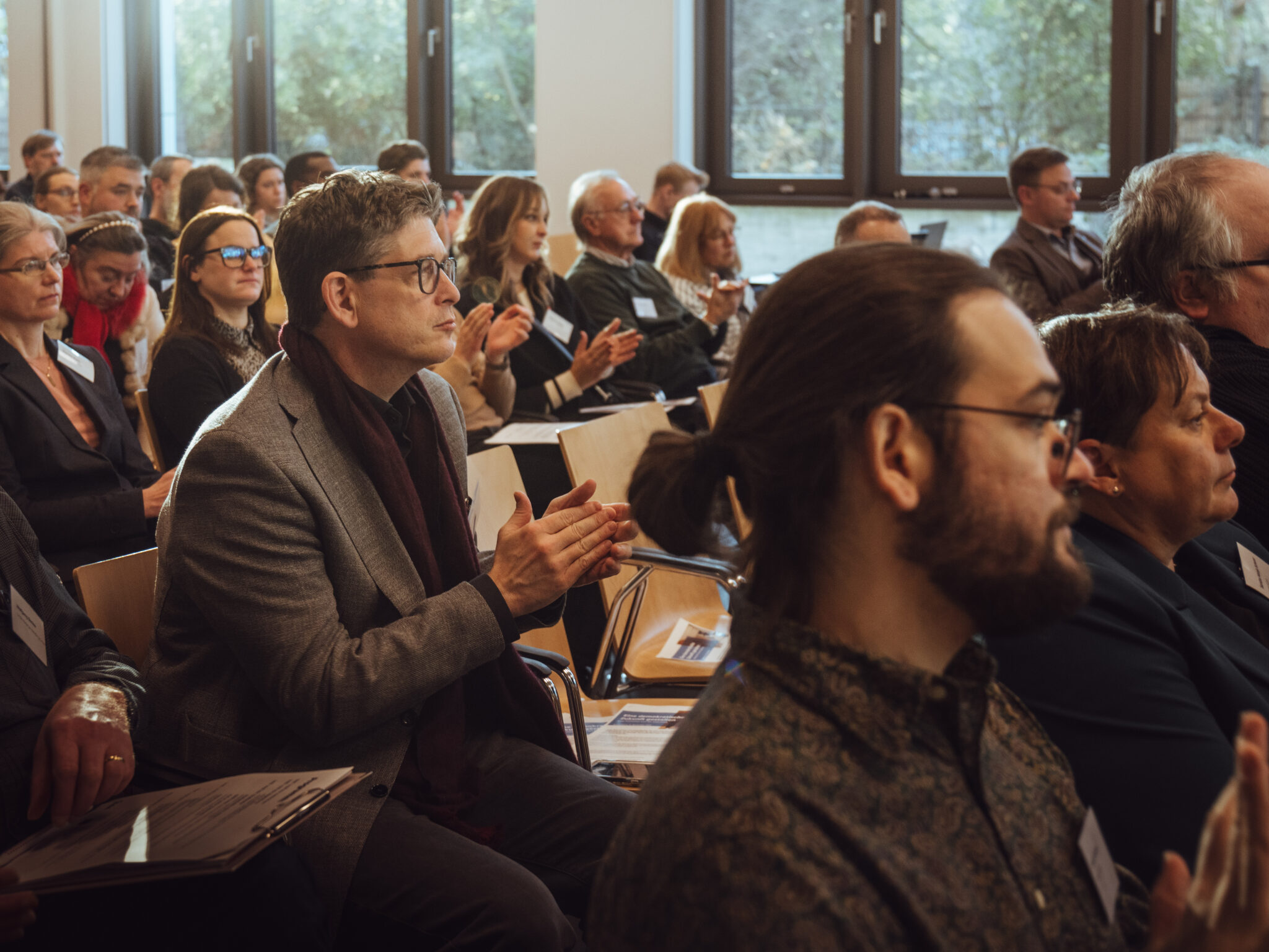 - Europäische Akademie der Arbeit Verschiedene Personen im Publikum applaudieren während einer Veranstaltung zu Ehren von Hugo Sinzheimer.