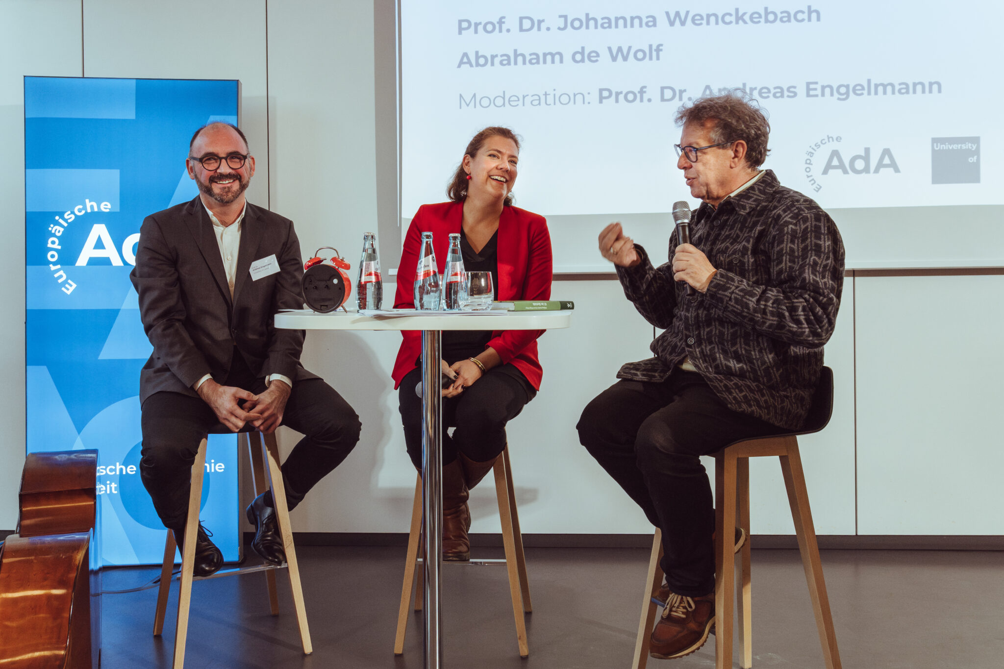 - Europäische Akademie der Arbeit Prof. Dr. Andreas Engelmann moderiert ein Gespräch mit Prof. Dr. Johanna Wenckebach und Abraham de Wolf an einem Tisch.