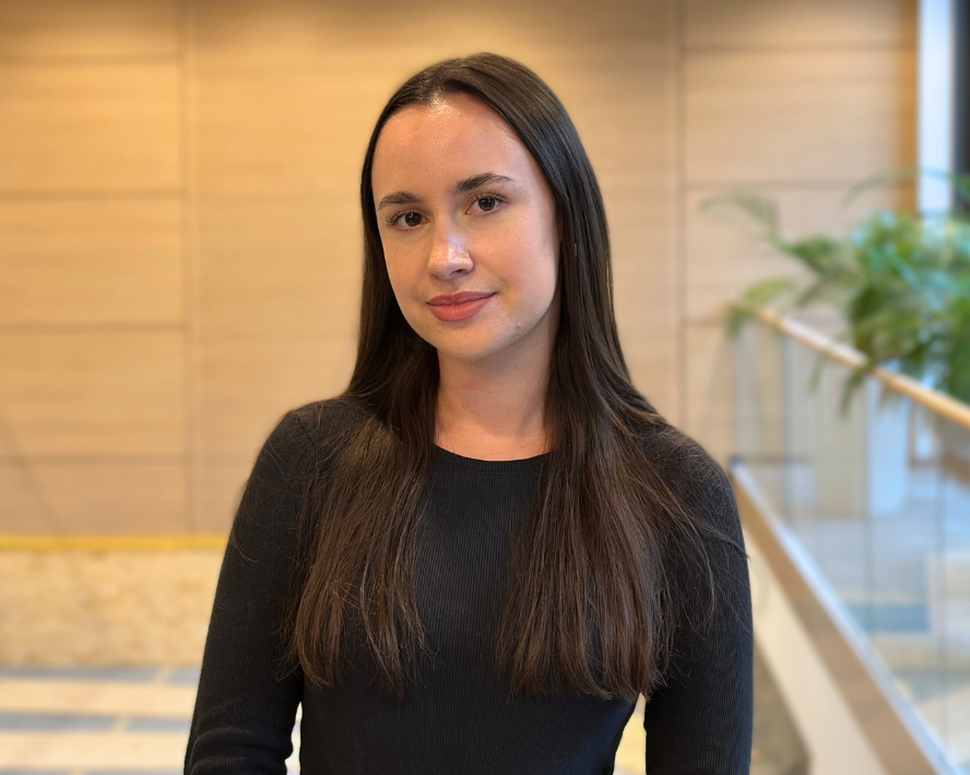 Franziska Monath steht in einem modernen Innenraum mit Holzverkleidung und Pflanzen im Hintergrund.